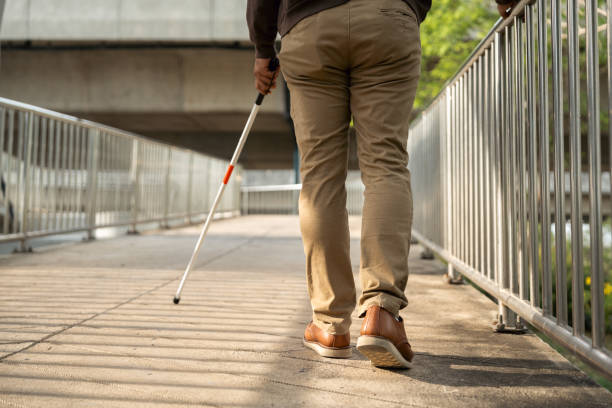 istock Young blind man walking in city with walking stick. Visually impaired man difficult to traveling on the road wearing sun glasses Cross the road cross the footbridge 2155805706