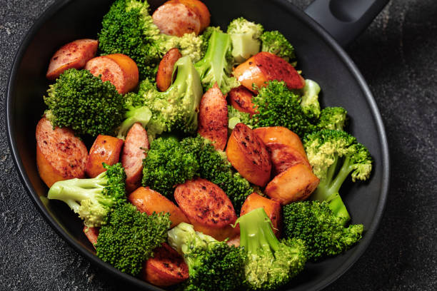 sausage and broccoli stir fry in skillet, close-up, dutch angle view