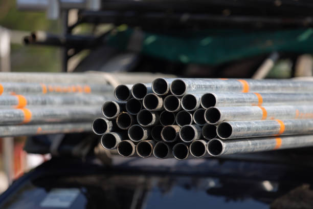 A pile of pipes with orange markings on them. The pipes are stacked on top of each other