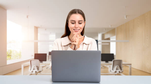 istock Cheerful young woman with laptop in office 2155808323