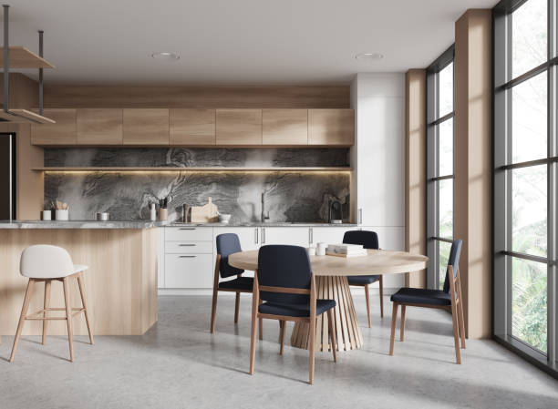 istock A modern kitchen interior design with wooden cabinets, dining table, chairs, and large windows with a nature view, light. 3D Rendering 2155808816