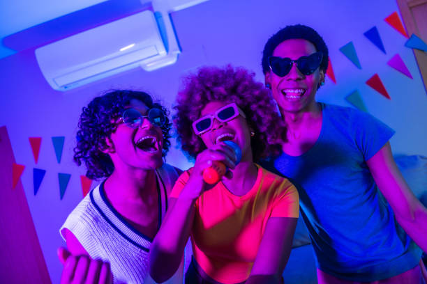 istock Happy multi-ethnic friends singing karaoke at night at the apartment 2155809404