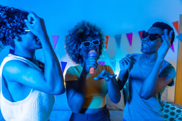 istock Happy friends having fun partying at home singing karaoke 2155809405