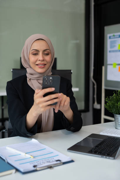 istock Happy business woman looking at cellphone screen, reading message, or email, communicating distantly with client from computer work in modern office. 2155811946