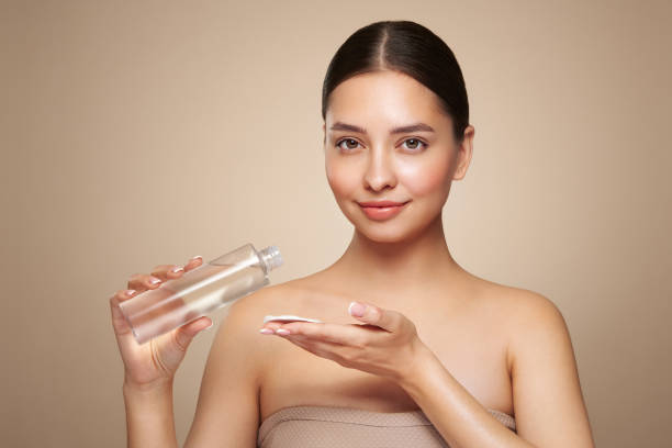 istock Smiling woman holds bottle with cosmetic tonic 2155812380