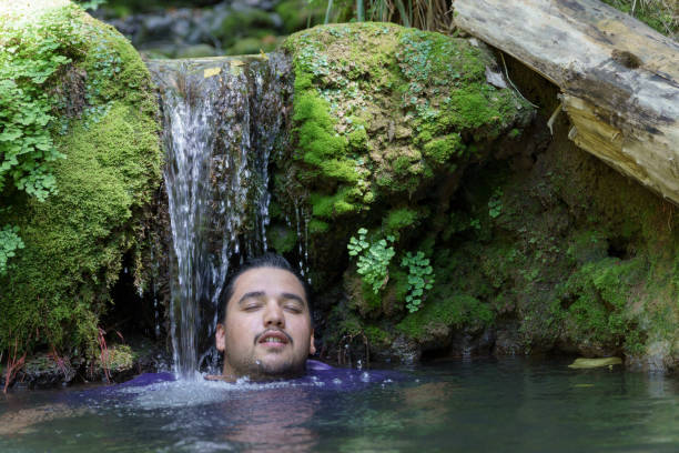 istock young dark-haired boy cooling off under a river waterfall 2155814445