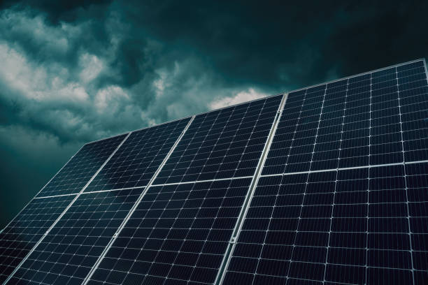 Solar panels photovoltaic cells against dark stormy clouds Solar panels photovoltaic cells against dark stormy clouds, selective focus glitch generator stock pictures, royalty-free photos & images