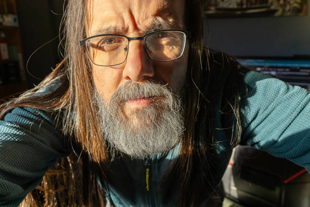 A man with glasses and a beard is looking at the camera. He has a expression of curiosity on his face
