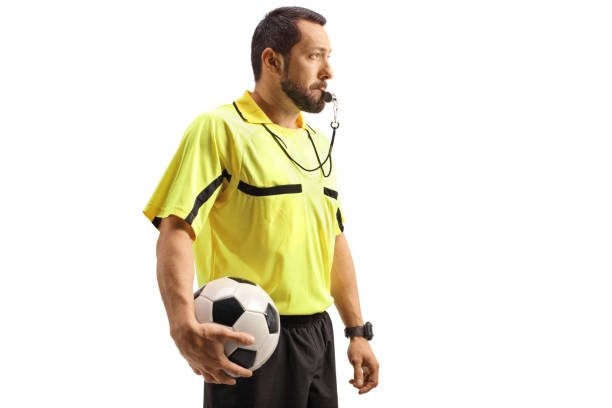 Football referee blowing a whistle and holding a ball isolated on white background