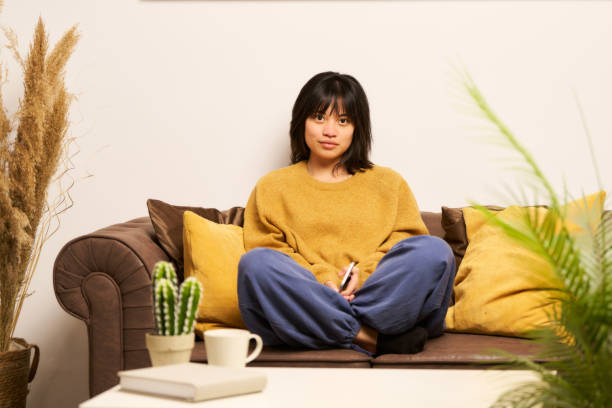 istock A woman is sitting on a couch with a book in her lap 2155818469