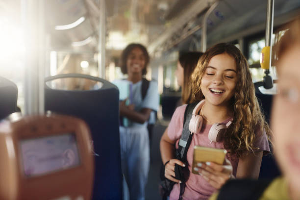 Happy schoolgirl text messaging on cell phone in a bus.