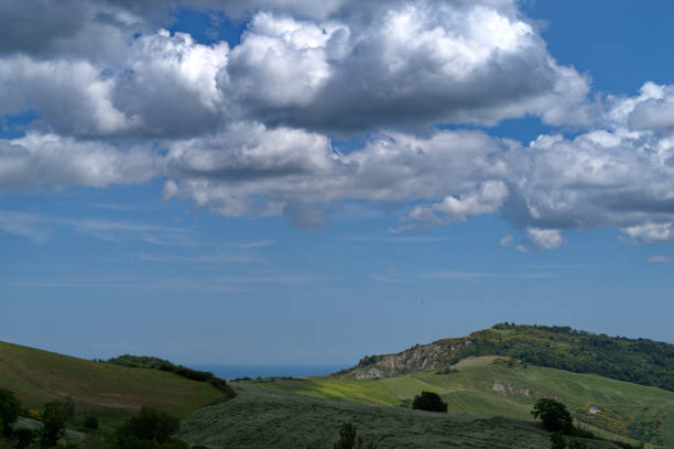 Hilly landscape of Montefeltro against partly cloudy sky and Adriatic sea