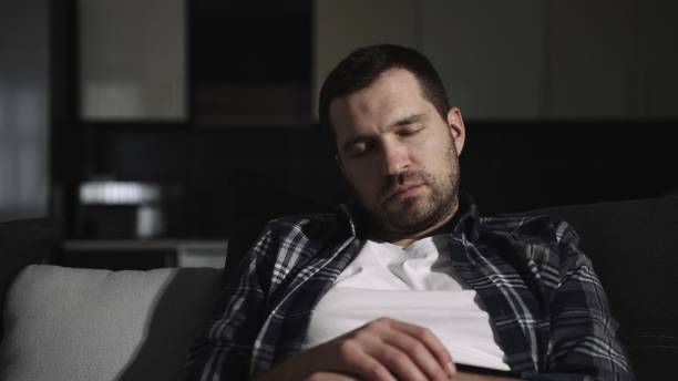 istock Tired guy resting sitting in a large comfortable sofa at home. Slow motion 2155826786