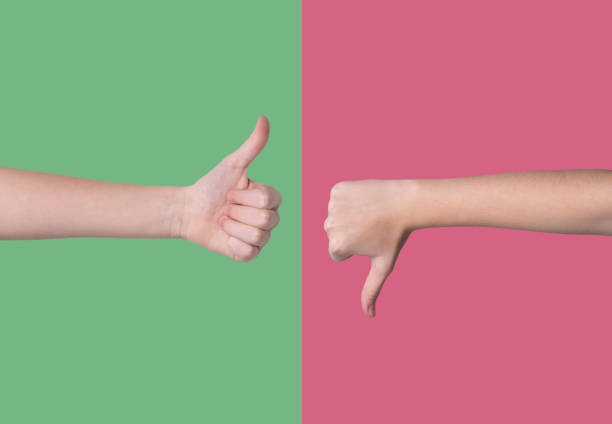 Two hands showing thumbs up and thumbs down gestures on a red and green background. The concept of sign language is like or dislike.