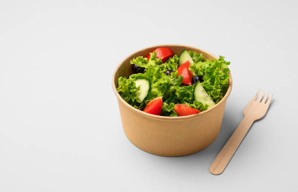 istock Fresh salad in eco-friendly container with wooden fork on light background. 2155827231