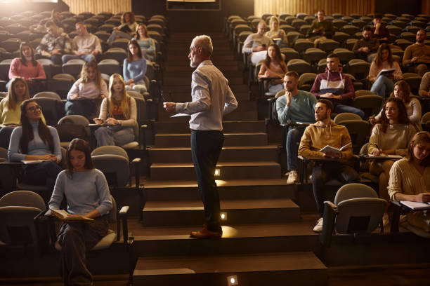 istock Senior professor talking to his students on a class at lecture hall. 2155833080