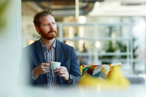 istock Pensive redhead businessman drinking coffee in the office. 2155833720