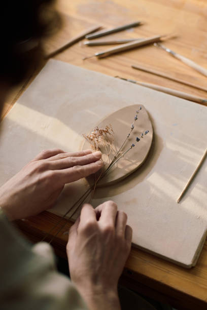 istock Unrecognizable Artisan Placing Dried Flowers Onto Clay Leaf 2155834320