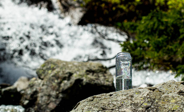 Reusable Water Bottle with clean water on a stone against mountain river