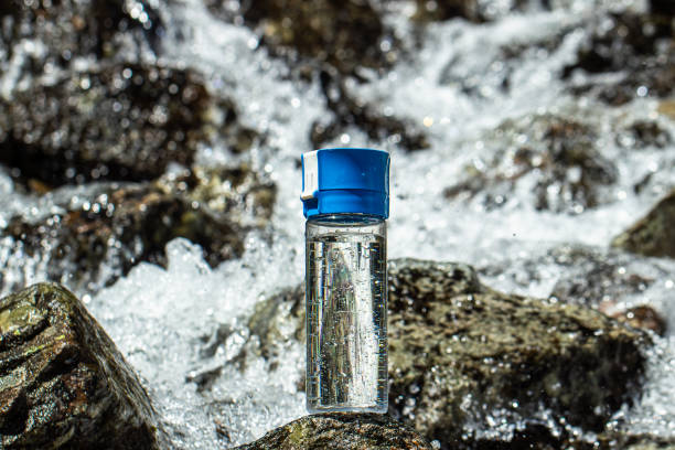 istock bottle with clean mineral water and mountain river waterfall background 2155835607