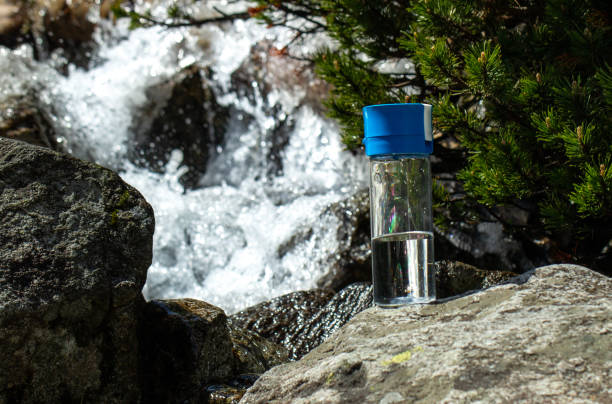 istock bottle with clean mineral water and mountain river waterfall background 2155835617