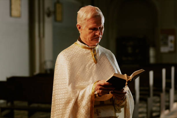 istock Senior Catholic Priest Reading Bible 2155837368