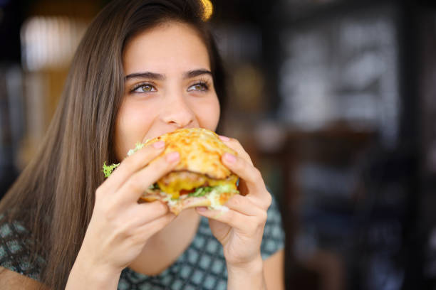 istock Happy woman eating hamburger in a restaurant 2155837559