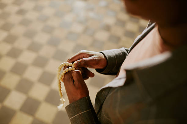 High angle view of unrecognizable Black male parishioner holding rosary in hands, copy space