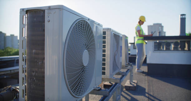 istock Maintenance worker or engineer wearing protective helmet and yellow vest examining AC unit fan outdoors 2155840420