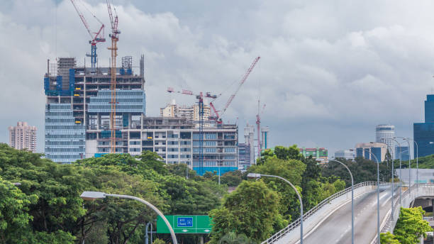 Construction site of a modern skyscraper in Singapore timelapse. Aerial view from above. Clouds on background and traffic on a road