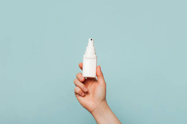 istock A hand holding a white spray bottle against a light blue background 2155845409