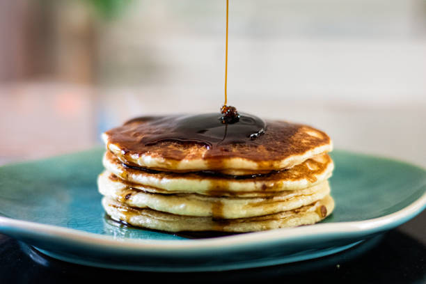 Tall stack of pancakes with rich maple syrup.