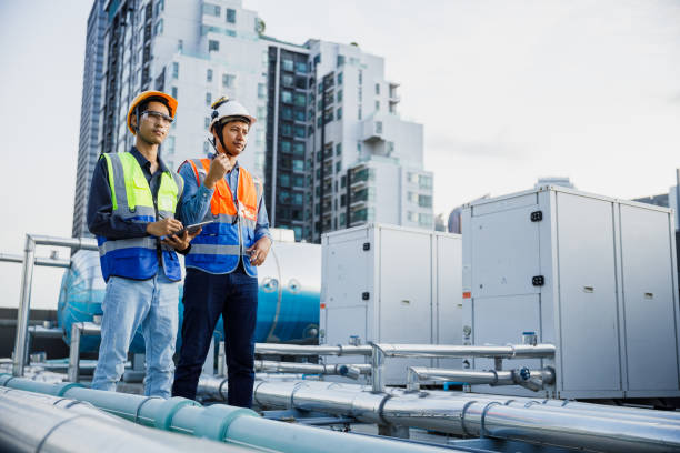 istock Team engineer holding tablet working at rooftop building construction. Male technician worker working checking hvac of office building. Engineering installing large air conditioning system. 2155847808