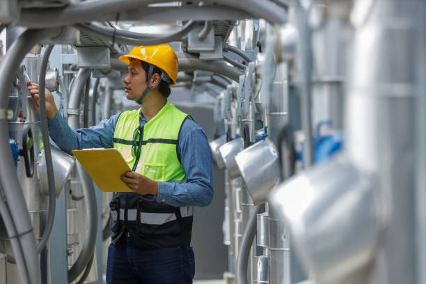 istock Male operator worker holding paperwork checking write record quality cooling air piping HVAC system at industrial building. Man engineer working on Heating Ventilation and Air conditioning system. 2155848480
