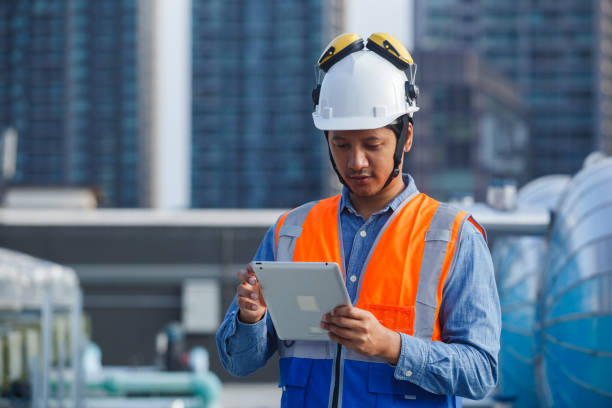 istock Asian man engineer holding tablet working at rooftop building construction. Male technician worker working checking hvac of office building. Engineering installing large air conditioning system. 2155848654