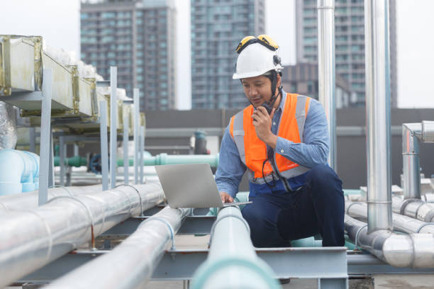 istock Man Industrial engineer using walkie talkie and laptop working at rooftop construction. Male technician working checking HVAC system building factory. Installing large air conditioning system. 2155848757