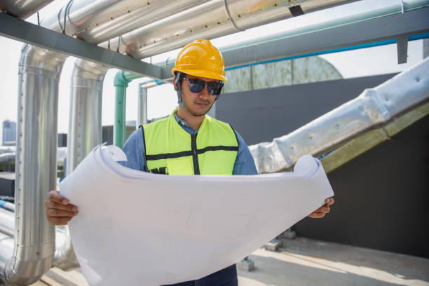 istock Male operator worker reading blueprint checking drawing plan cooling air piping HVAC system at industrial building. Man engineer working on Heating Ventilation and Air conditioning system. 2155848818