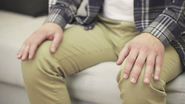 istock Nervous man sitting on sofa while holding hands on knees. Slow motion 2155850622
