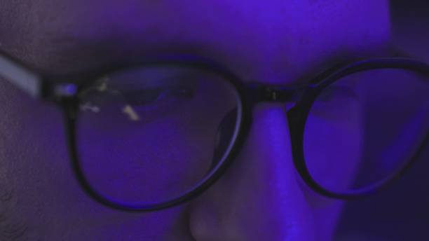 istock Man with glasses in the dark looking at computer screen, watching dj show online 2155850914