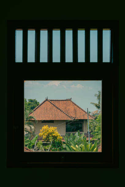 istock Traditional house framed by a window, surrounded by greenery 2155863532