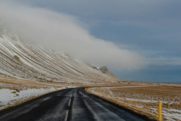 Road through snow-covered mountains under a cloudy sky Iceland no people outside