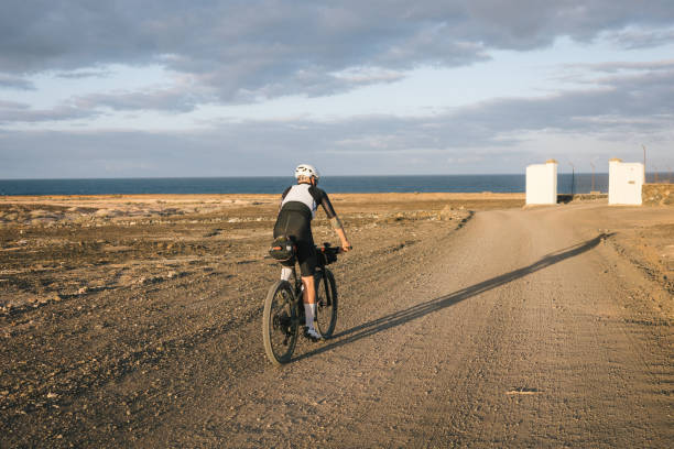 istock Road bicyclist rides through desert landscape 2155866137