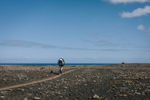 istock Road bicyclist rides through arid landscape 2155866363