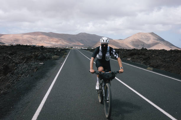 istock Road bicyclist rides through rural landscape 2155866477