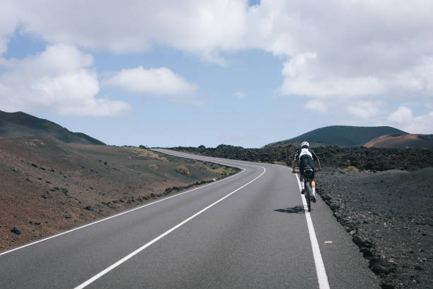 istock Road bicyclist rides through rural landscape 2155866506