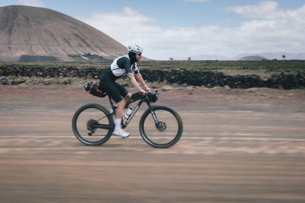 Road bicyclist rides through rural landscape