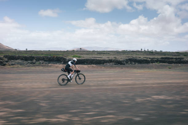 istock Road bicyclist rides through rural landscape 2155866639