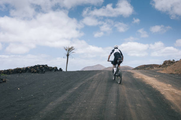 istock Road bicyclist rides through rural landscape 2155866668