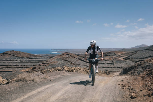 istock Road bicyclist rides through desert landscape 2155866827