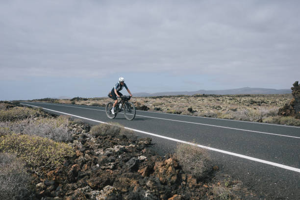 istock Road bicyclist rides through rural landscape 2155867116